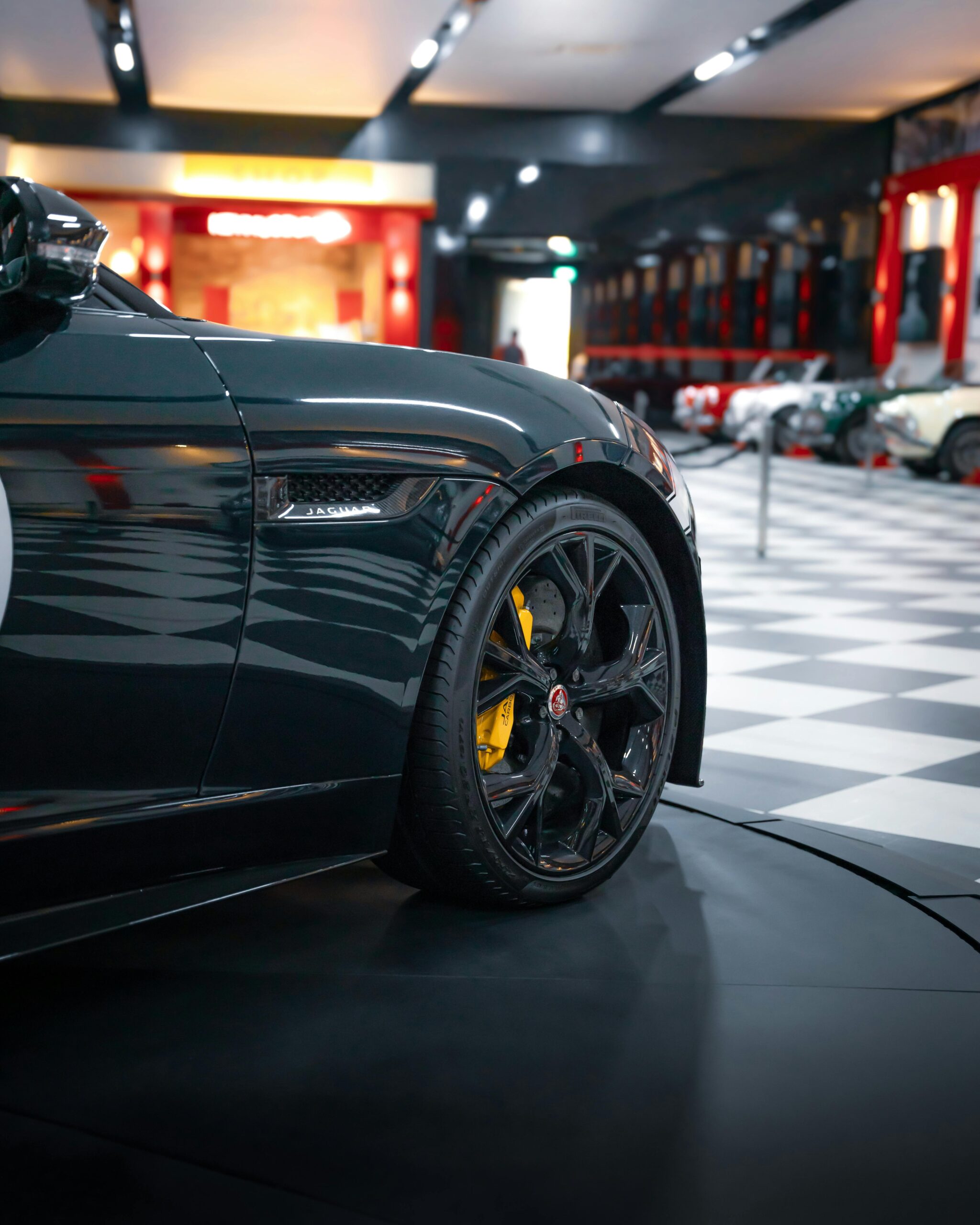 Close-up of a classic Jaguar car on display in a stylish indoor exhibition showroom with elegant detailing.